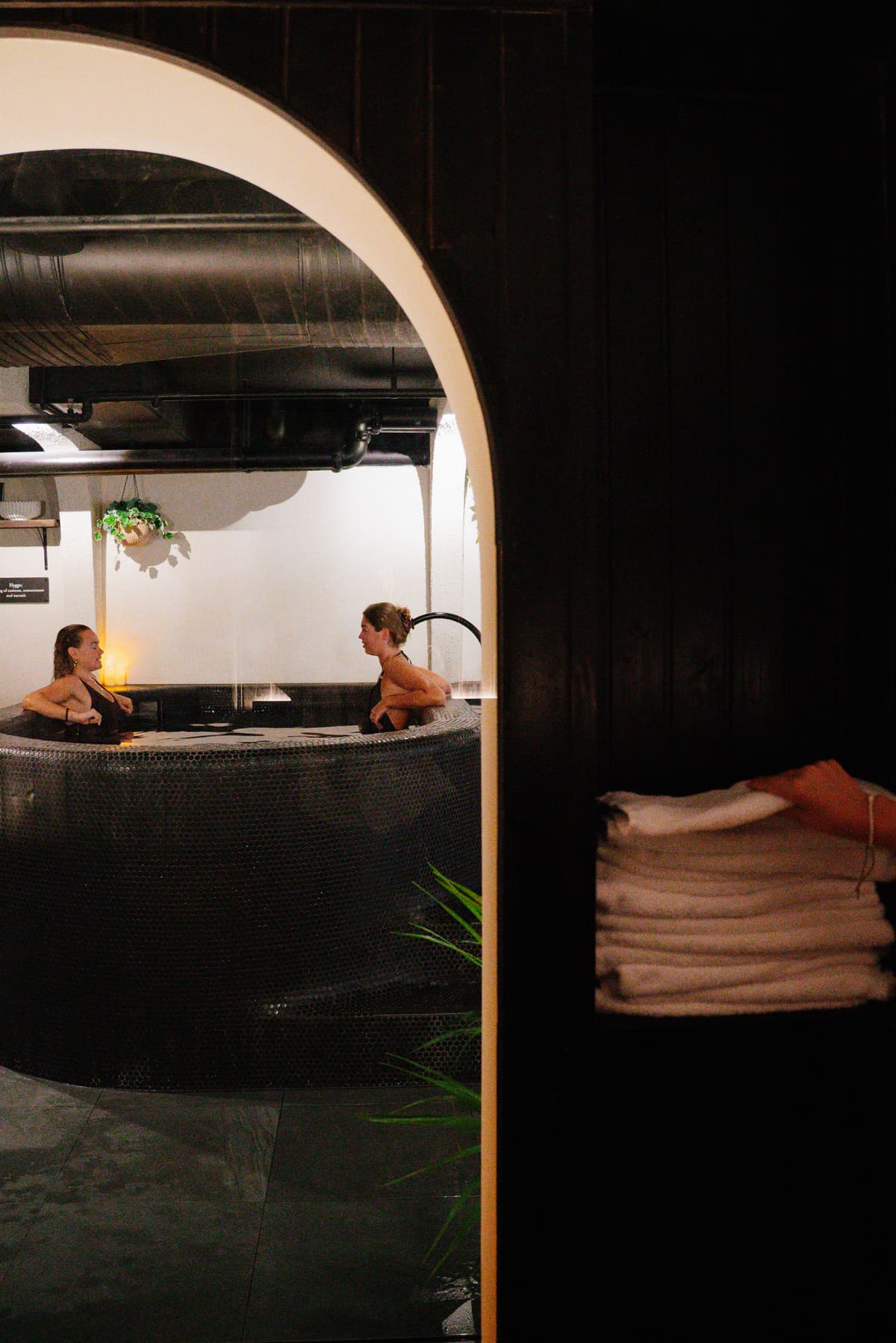 The round stainless-steel cold plunge waiting in a dark stone room at Navia Bathhouse
